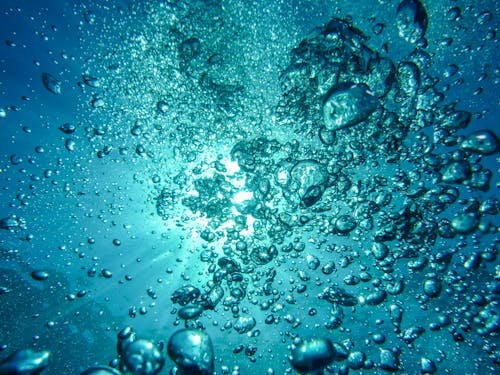 Sott’acqua con bolle d’aria ascendenti verso la superficie, luce filtrata dall’acqua blu.