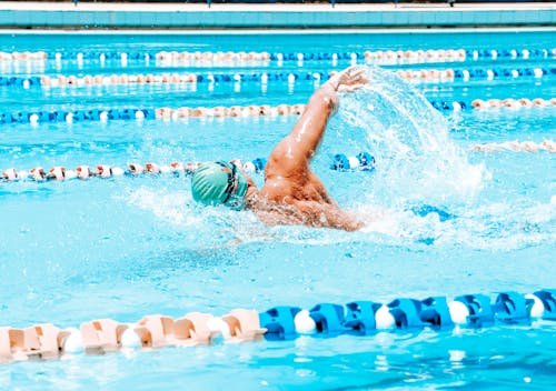 Nuotatore in stile crawl mentre nuota in piscina, bracciata ampia e nuotate energiche durante un allenamento di stile nuoto per dimagrire
